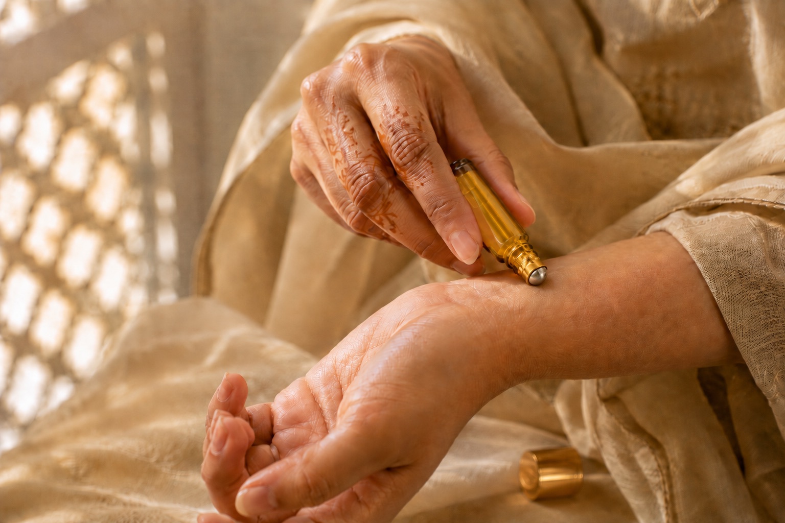 Applying ARFA KHUSHBOO attar oil to the wrist from a gold roll-on bottle